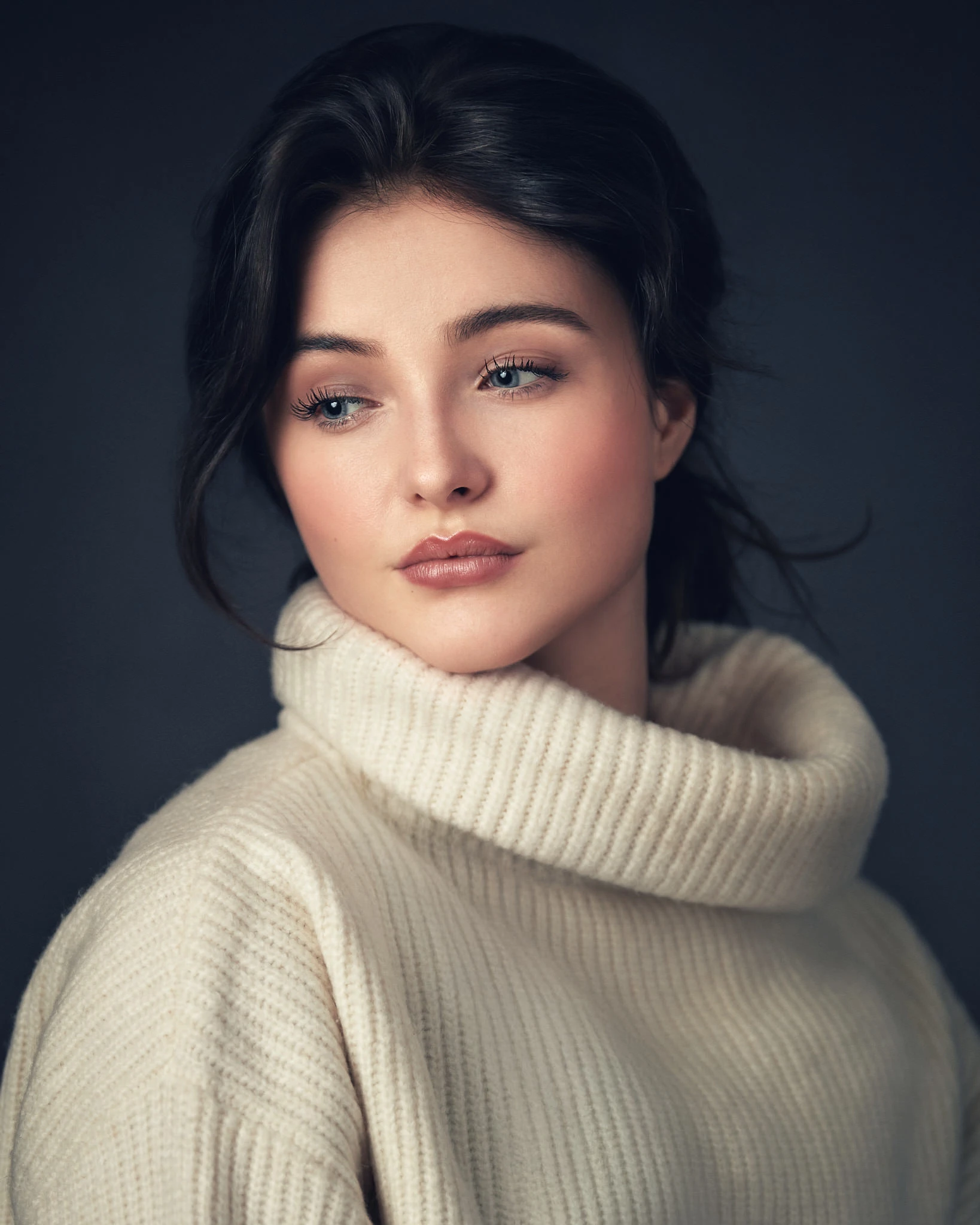 Fine art portrait of a young woman in a cream turtleneck jumper with soft painterly lighting and muted tones